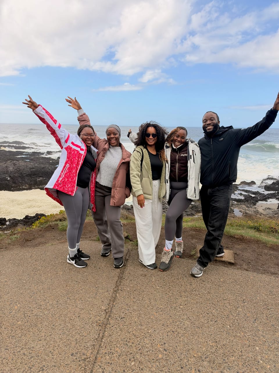 Five friends cheering on a viewpoint above the rocky coast